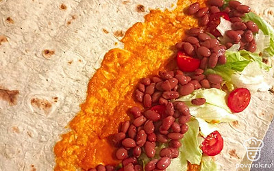 На лист лаваша выложить кабачковую икру, следом лист салата, черри и консервированную фасоль.