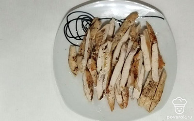 Подготовьте куриное филе, нарезав его на пластины и посыпав равномерно перцем. Далее выложите его на раскаленную сковороду и обжаривайте на среднем огне до готовности, а именно появления румяной корочки. После остывшее мясо нарежьте уже на более мелкие кусочки.