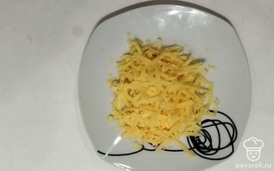 Распакуйте брусок сыра, отрежьте от него нужный по весу кусочек и потрите его в миску на крупной терке соломкой. Оставшийся кусок отправьте в холодильник, а измельченный далеко не убирайте – он скоро пригодится.