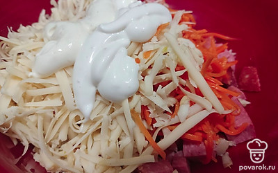 Нарежьте кубиками колбасу. Добавьте к колбасе натертый на крупной терке сыр и чеснок. Далее добавьте к этой массе морковь и соус. Тщательно все перемешайте.