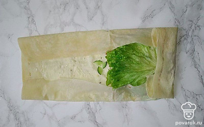 Лист лаваша намажьте чесночным соусом. С одной стороны листа распределите мясо, сладкий перец, огурцы и сыр и накройте листиком салата. Заверните лаваш, сначала подогнув края по бокам, а затем - в виде рулета.