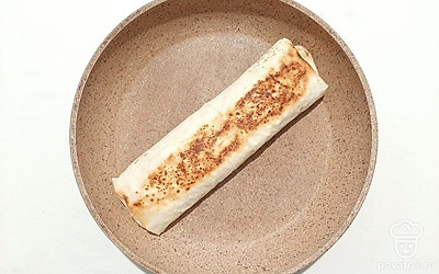 Сверните лаваш с начинкой в плотный рулет. Выложите заготовку швом вниз на разогретую сухую сковороду, при этом слегка прижмите лопаткой. Прожарьте с двух сторон до румянца.