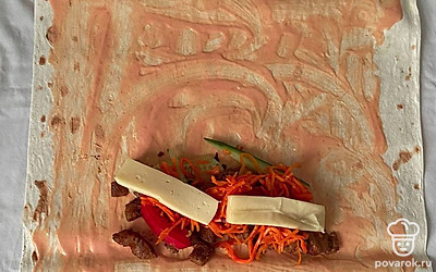 Смешайте в миске кетчуп и майонез. Смажьте лаваш этим соусом. Выложите на лаваш мясо, огурцы, помидоры, морковь по-корейски, в конце сыр.