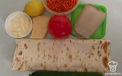 Промойте помидор и огурец. Разморозьте мясо кальмара. Нарежьте огурец и помидор дольками. Натрите сыр на терке. Разогрейте духовку до 220 ℃.