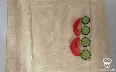 Положите кальмар в кипящую воду на 5 минут. Добавьте в майонез лимонный сок и перемешайте. Разложите лаваш и смажьте соусом. На край выложите огурец и помидор.