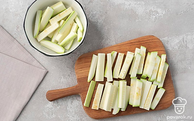 Разрежьте кабачок поперек на три части. Каждую часть нарежьте пластинками толщиной около 5-6 мм. Сами пластинки нарежьте тонкими брусочками.