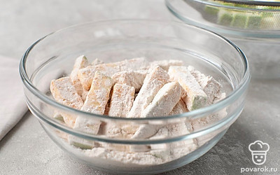 Переложите кабачки в мучную смесь. Закройте миску крышкой и хорошо встряхните, чтобы мука со специями равномерно распределилась по брусочкам.