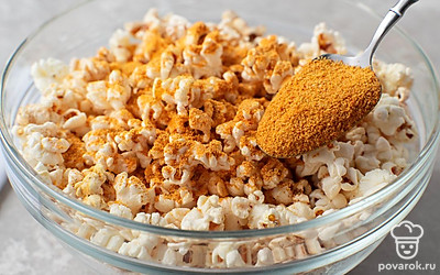 Насыпьте получившийся сырный порошок в емкость с попкорном. Закройте ее крышкой и встряхните несколько раз, чтобы порошок равномерно распределился по попкорну. Переложите сырный попкорн в салатник.