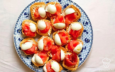 Перепелиные яйца разрежьте на половинки. Уложите половинки яиц на тарталетки возле розочек из рыбы или прямо сверху на них.