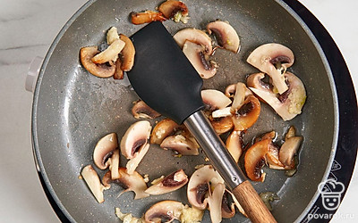 Нашинкуйте шампиньоны ломтиками. Очистите и пропустите чеснок через пресс. Разогрейте на сковороде на среднем огне половину оливкового масла. Выложите чеснок. Жарьте 1 минуту. Добавьте к чесноку грибы. Жарьте до золотистого цвета 8-10 минут.