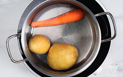 Положите в кастрюлю картофель и морковь. Залейте овощи водой и поставьте на огонь. Дождитесь кипения, а затем варите ингредиенты еще 20-25 минут. Остудите овощи и почистите.