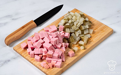 Нарежьте колбасу и маринованные огурцы кубиками.