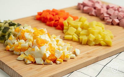 Измельчите продукты. Докторскую колбасу, огурцы, отварную морковь и картошку нарежьте кубиками небольшого размера. Яйца измельчите удобным способом.