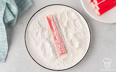 Насыпьте в тарелку 1 ст.л. муки. Обваляйте в ней каждую крабовую палочку.