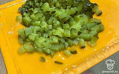 Нарежьте кубиками соленый огурец.