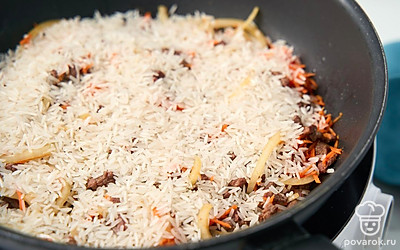 Засыпьте в сковороду рис, прогрейте его с мясом и овощами, равномерно перемешивая, 1-2 минуты.