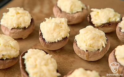 Смажьте пергамент топленым маслом. Выложите на противень шампиньоны. Отправьте их в духовку, разогретую до 200°С, на 15 минут.