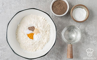 Соедините в миске муку, разрыхлитель, куркуму, соль, перец и сушеный чеснок. Хорошо перемешайте. Налейте в сухую смесь воду, хорошенько перемешайте кляр до однородности.