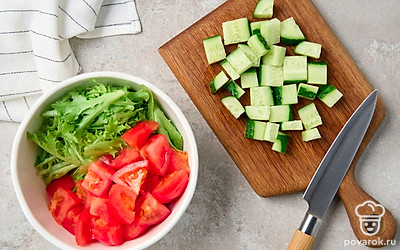 Нарвите листья салата руками, нарежьте помидоры и огурец кубиками со стороной около 1,5 см. Выложите овощи в салатник.