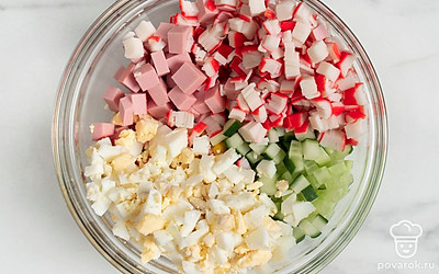 Нарежьте яйца, колбасу, огурец и крабовые палочки кубиками со стороной около 6-7 мм.