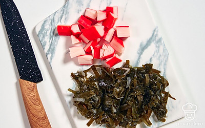 Нарежьте крабовые палочки средними ломтиками. Мелко порубите морскую капусту.