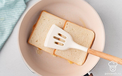 На яйцо положите 2 кусочка хлеба. Прижмите их к яйцу лопаткой.