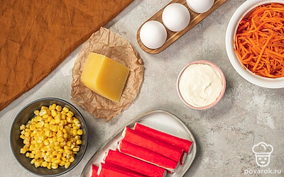 С крабовых палочек снимите упаковку. Яйца отварите вкрутую, остудите, почистите. Отложите вареный белок 1 яйца для украшения. Помойте и отварите морковь для украшения. Морковь по-корейски откиньте на дуршлаг, дайте стечь лишней жидкости. Укроп вымойте, обсушите на бумажных полотенцах. Откройте банку с консервированной кукурузой, слейте жидкость. Приготовьте широкое плоское блюдо, кулинарное кольцо и зубочистки.