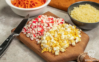 Измельчите продукты. Крабовые палочки нарежьте небольшими кубиками. 5 палочек разрежьте на части длиной приблизительно по 5 см каждая. Сыр измельчите при помощи терки со средними ячейками. Яйца нарежьте маленькими кубиками.