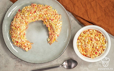 Соберите салат. На блюдо установите кулинарное кольцо. В миске соедините сыр, крабовые палочки, корейскую морковь, консервированную кукурузу и яйца, заправьте майонезом, перемешайте. Полученную массу выложите на блюдо вокруг кольца, слегка утрамбуйте. Аккуратно уберите кулинарное кольцо. Поставьте салат в холодильник на 4-5 часов.