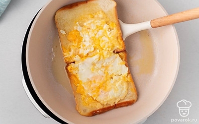 Через минуту аккуратно переверните ломтики хлеба вместе с яйцом. Подрумяньте хлеб еще 1 минуту. Уберите сковороду с огня.