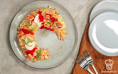 Поверх салата распределите веточки свежего укропа, выкладывая их по кругу. В крабовые палочки воткните зубочистки так, чтобы края немного торчали вверх. На кончиках закрепите кусочки отварной моркови в виде языка пламени, установите «свечи» по кругу «венка». Украсьте салат цветочками, вырезанными из яичного белка, в серединку каждого положите по зернышку кукурузы.