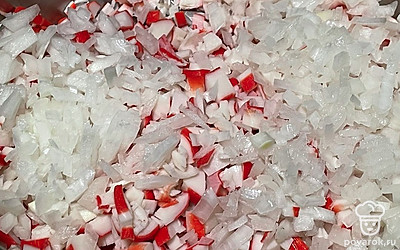 Лук мелко нарежьте и отправьте к крабовым палочкам.