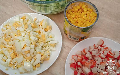 Яйца отварить и нарезать кубиками размером с кукурузу. Также нарезать свежие огурцы и крабовые палочки. 