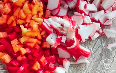 Крабовые палочки нарезать на кусочки, а болгарский перчик на мелкий кубик. Выложить в приготовленную посуду.