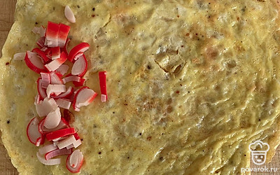 На яичный блинчик выложить крабовые палочки.