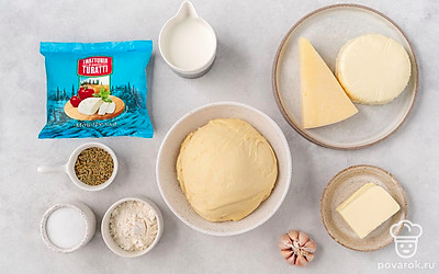 Разморозьте тесто. Помойте и почистите чеснок. Разогрейте духовку до 180°С. Застелите противень пергаментом.