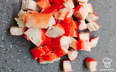 Нарежьте кубиками крабовые палочки.