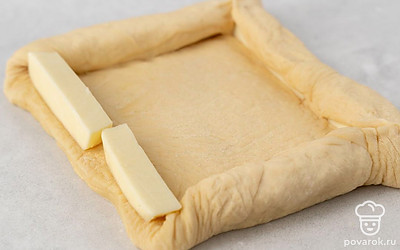 Раскатайте тесто в небольшой прямоугольник. Нарежьте сулугуни на палочки толщиной 1 см. Выложите их по периметру пиццы. Заверните тесто внутрь, чтобы сформировать сырные бортики.