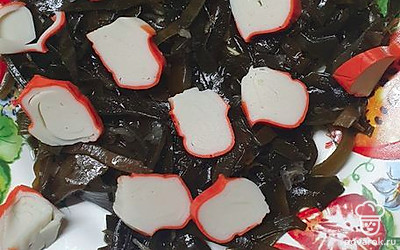 Выложить морскую капусту и порезать крабовые палочки.