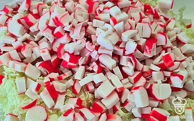 Порежьте крабовые палочки. Добавьте к капусте.