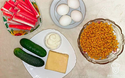 Отварите яйца. Помойте огурцы. Пересыпьте кукурузу из банки в глубокую тарелку. Отрежьте сыр. Отмерьте майонез.