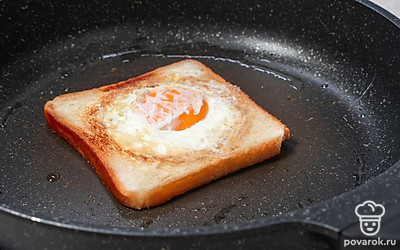 Аккуратно лопаткой переверните хлеб с яйцом на другую сторону, чтобы желток запечатался внутри. Накройте сковороду крышкой. Уменьшите нагрев до минимального. Готовьте еще 2 минуты.