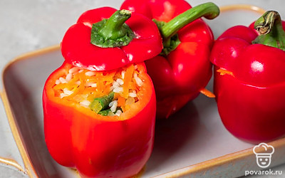 Снимите рис с овощами с огня и немного остудите. Затем переложите начинку в подготовленные перцы. Поставьте нафаршированные перцы вертикально в форму для запекания, накройте каждый верхней частью с плодоножкой. Поставьте форму с перцами в разогретую до 180℃ духовку и готовьте 30 минут.