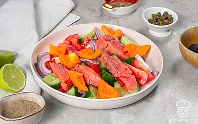 Приготовьте салат. Соедините в салатнице нарезанные огурцы, помидоры, лук, перец, маслины, каперсы и сыр фета. Полейте маслом, соком лайма, приправьте орегано и перемешайте. Сверху положите кусочки филе семги.