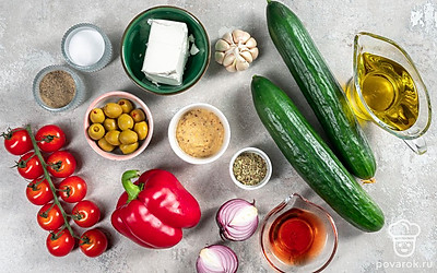 Сыр фета нарежьте крупными кубиками. Огурцы помойте и нарежьте кубиками. Помидоры черри помойте и разрежьте пополам. Лук почистите, помойте и нарежьте полукольцами. Зубчики чеснока почистите, помойте и измельчите. Ополосните и обсушите листья салата для подачи.