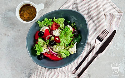 Греческий салат можно подать на тарелках, украшенных листовым салатом.