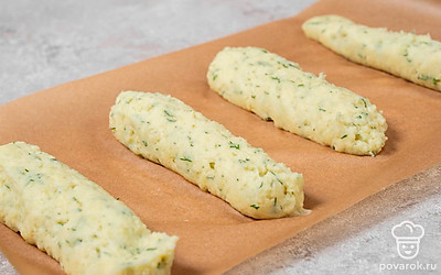 Переложите получившееся пюре в кондитерский мешок. Застелите стол листом пергамента. Отсадите на него длинные полоски картофельного пюре.