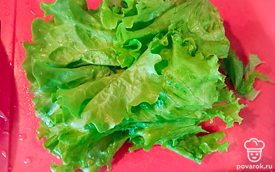 Помойте и чуть отожмите листья салата (можно положить на салфетку, чтобы стекла вода).