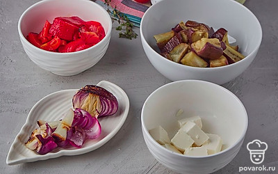 Когда овощи запеклись, дайте им остыть. После снимите шкурку с болгарского перца. Нарежьте печеные овощи на крупные произвольные кусочки. Маслины разрежьте пополам, помидоры нарежьте произвольно. Сыр фета нарежьте кубиком.