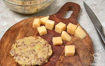 Нарежьте сыр небольшими кусочками. Возьмите немного пюре и сформируйте из него небольшую лепешку. 